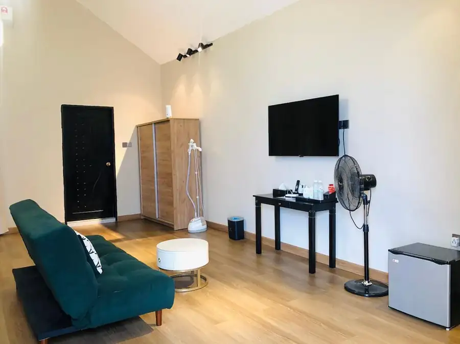 Comfortable living area inside the Bedroom Deluxe 1 Bed at Turtle Seaweed Resort featuring a teal sofa, flat-screen TV, and modern furnishings.